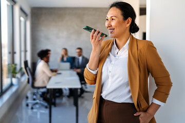 A confident businesswoman leads her busy office life, multitasking with smartphone communication