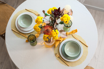 Beautiful table setting with bouquet of flowers, tea and candles in light dining room, top view
