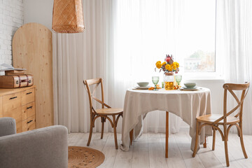 Interior of stylish room with beautiful flowers on served dining table