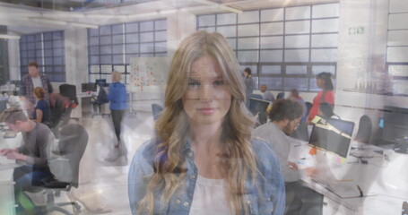 Young woman in modern office, colleagues working on computers in background