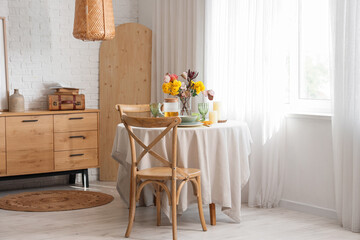 Interior of stylish room with beautiful flowers on served dining table