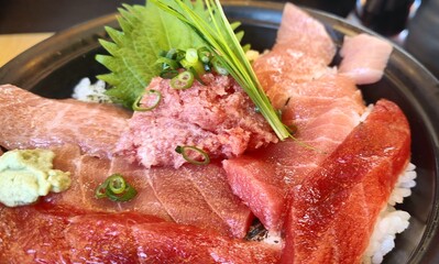 Close-up, top-down view of a colorful Japanese Kaisendon seafood rice bowl featuring assorted sashimi like tuna, yellowtail, salmon, and shirasu, topped with ikura (salmon roe), tamago, ginger, and wa
