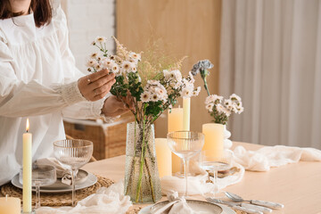Young woman serving table with beautiful flowers in dining room