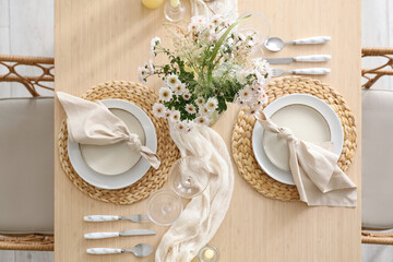 Beautiful table setting with bouquet of flowers and candles in light dining room