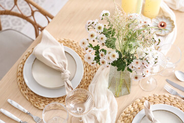 Beautiful table setting with bouquet of flowers and candles in light dining room