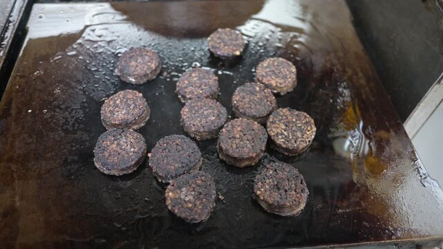 Black pudding slices sizzling on a hot griddle top