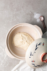 overhead view of focaccia dough proofing in a claypot, top view of a high hydration focaccia bread dough resting in a donabe, process of making high hydration focaccia