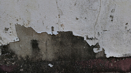 Close-up of a distressed and dirty cement or concrete wall. The peeling white paint reveals darker, gritty, and stained layers of gray and black mold or dirt underneath