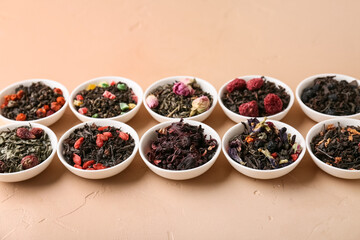 Bowls with different dry fruit tea on beige grunge background, closeup