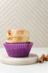Close-up of a vanilla cupcake in a pink wrapper with buttercream frosting, cupcake in a pink liner with a cinnamon frosting