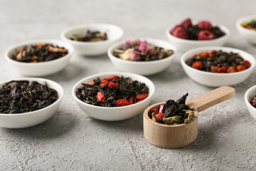 Bowls with different dry fruit tea on grey grunge background, closeup
