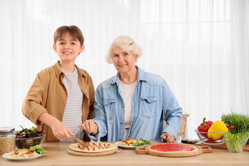 Senior woman with her grandson making pizza in kitchen