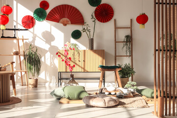 Interior of light living room with tea set, pillows and Chinese decor