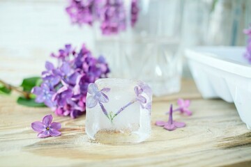  Lilac flowers, ice cubes and a glass of water on a light background and lilac flowers in a vase