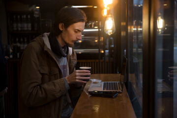  remote workers. Working from Anywhere.  a young man is working on a laptop in a cafe and drinking coffee