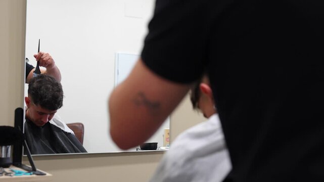 Hairdresser begins applying bleach and oxidant mix to customer's hair seen through mirror reflection