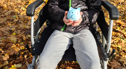 Person in Wheelchair Holding Piggy Bank in Fall Foliage