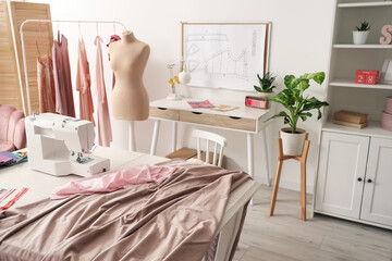 Interior of stylish atelier with mannequin, tailor's tables and clothes rack
