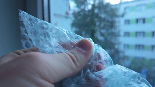 Tense scene of hand pressing bubble wrap symbolizing stress and anxiety