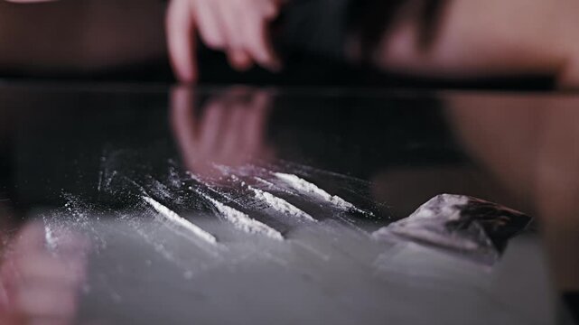 Macro view, white powder prop lines on glass with blurred hand moving behind