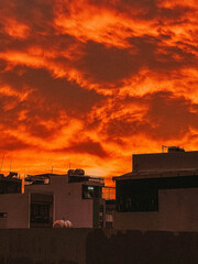 Fototapeta premium Bright orange sunset sky with glowing clouds above city rooftops