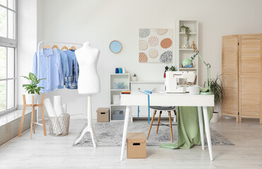 Interior of stylish atelier with mannequin, tailor's workplace and clothes rack