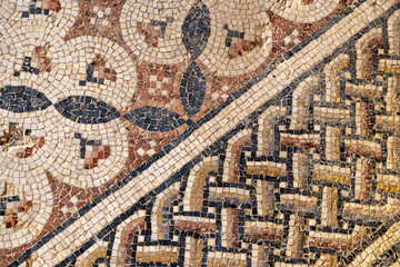 Close view of an ancient floor mosaic with weathered tesserae forming geometric diamond motifs, ideal for archaeology themes, art history contexts, texture uses and Mediterranean heritage 