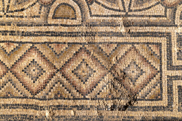 Close view of an ancient floor mosaic with weathered tesserae forming geometric diamond motifs, ideal for archaeology themes, art history contexts, texture uses and Mediterranean heritage 