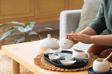 Woman pouring Asian tea into cup on table at home, closeup