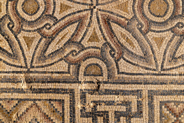 Close view of an ancient floor mosaic with weathered tesserae forming geometric diamond motifs, ideal for archaeology themes, art history contexts, texture uses and Mediterranean heritage 