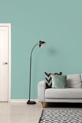 Black lamp and sofa near green wall in living room