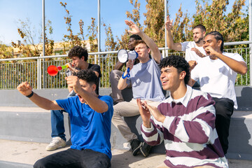 Multiethnic young male friends are enthusiastically cheering and supporting their favorite sports...