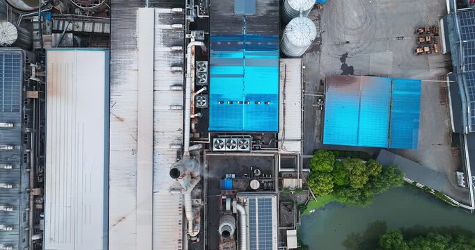 Aerial shot of industrial factory building roof with ventilation equipment and solar panel in industrial zone.