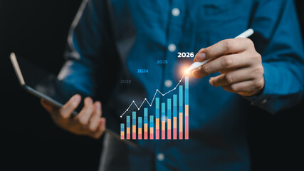 Professional man uses a stylus to point at a glowing financial bar chart and line graph, strategic business planning, investment analysis, and market growth trajectory from 2023 to 2026.