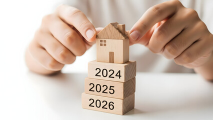 Hands holding wooden blocks forming a house with years stacked below it