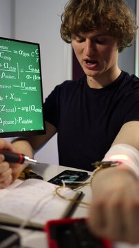 Vertical screen biohacker experiments with wearable chip and sensors at home desk connecting electronics testing signals recording results and exploring human enhancement and future biohacking