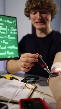 Vertical screen biohacker adjusts wearable chip and sensors on arm at home desk testing electronics recording data and exploring self enhancement biohacking and future human technology