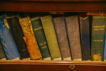 Close-up of heavily worn vintage book spines showing peeling covers and aged textures. An archival collection representing history and long-preserved literature.