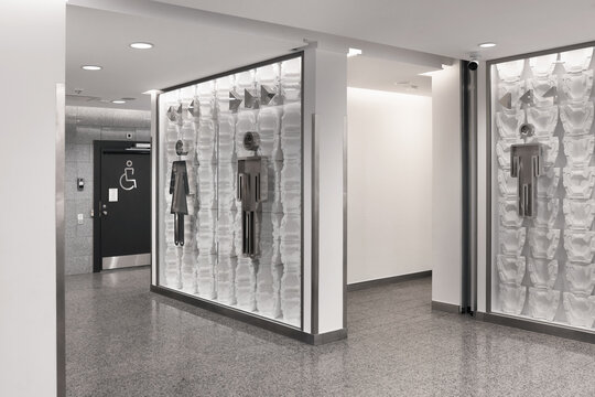 Modern public restroom entrance with metal gender signs and accessible toilet door in a clean hallway.
