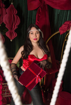 A young beautiful woman dressed in gloves stands in a hotel interior and holds a gift