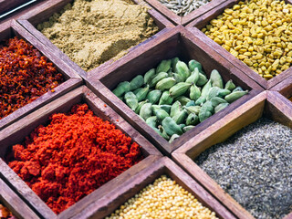 Colorful spices arranged in wooden boxes at a market in the afternoon sun for cooking and flavoring meals