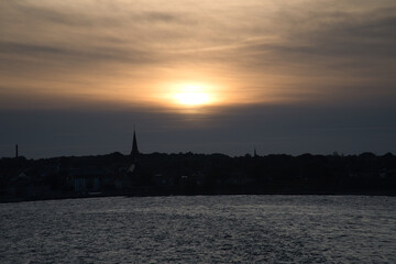 Fototapeta premium Sunset over the sea with boat trail and silhouette on the horizon