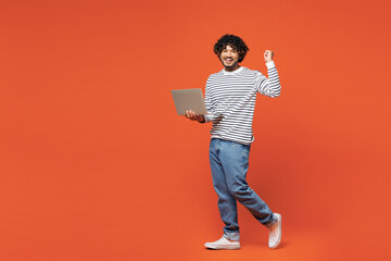 Full body young smiling happy IT Indian man he wear striped sweatshirt casual clothes hold use work...