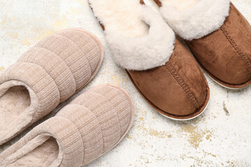 Two pairs of soft slippers on light grunge background. Top view