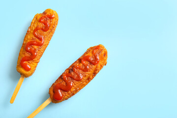 Tasty corn dogs with ketchup on blue background