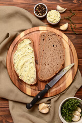 Board of bread slices with fresh butter and different spices on wooden background