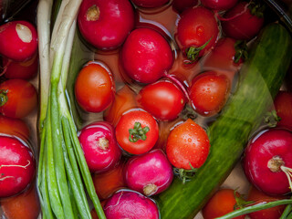 Bunch of fresh vegetables rinsed in the bowl with water in the sink, close up of veggies in the bowl covered with water drops.