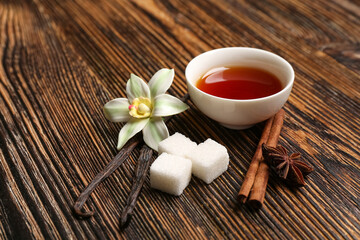 Composition with vanilla extract, sticks, flower and spices on wooden background