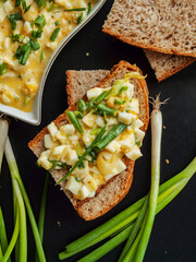 Egg sandwich salad with mayonnaise and green leek onion on fresh crusty piece of bread.
