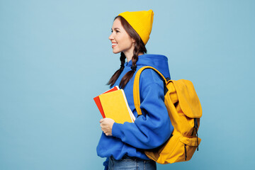 Side profile view young smart woman student she wear casual clothes backpack bag hold books isolated on pastel plain light blue color background studio portrait High school university college concept